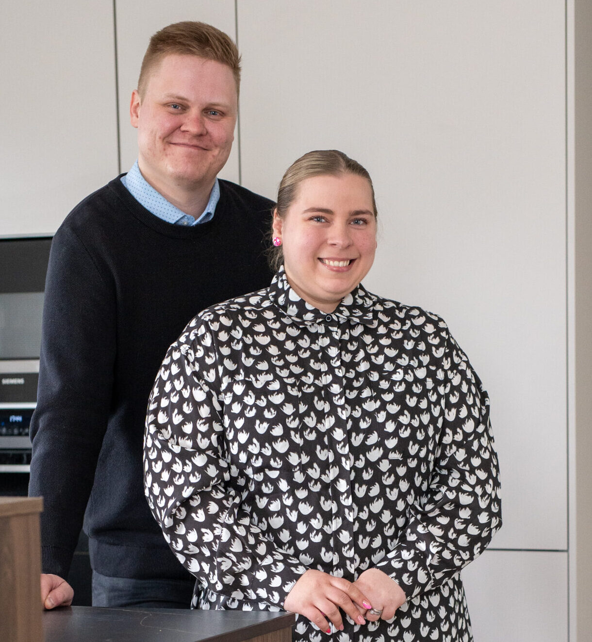 pariskunta ja koira keittiössä katsoen kameraan